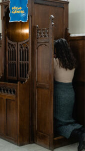 Mulher ajoelhada no confessionário vivendo o sacramento da confissão e experimentando a misericórdia de Deus.