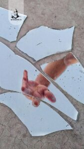 cacos de espelho quebrado que reflete uma mão